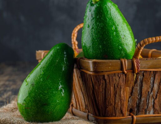 Avocado behind Brown basket and on it another avocado fruit