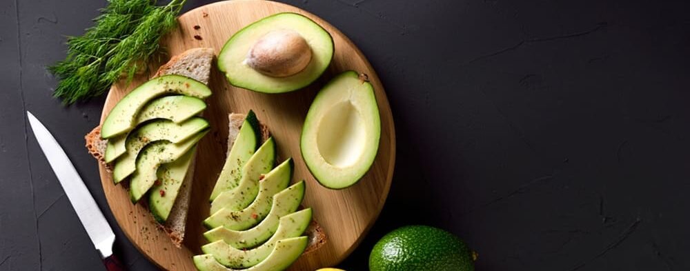 On a wooden plate slice fresh avocados fruit